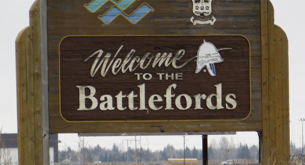 A large wooden sign in a field. In white letters, the sign reads: Welcome to the Battlefords.