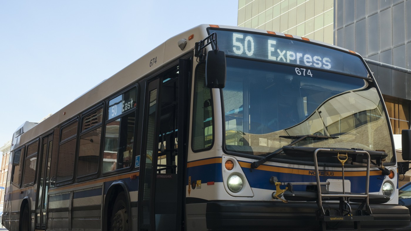 Photo of the 50 Express city of Regina bus in front of a tall office tower.