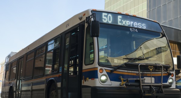 Photo of the 50 Express city of Regina bus in front of a tall office tower.